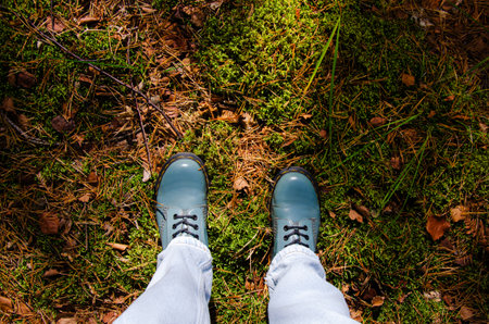 Top view of feet on bright green moss with autumn leaves and pine needles