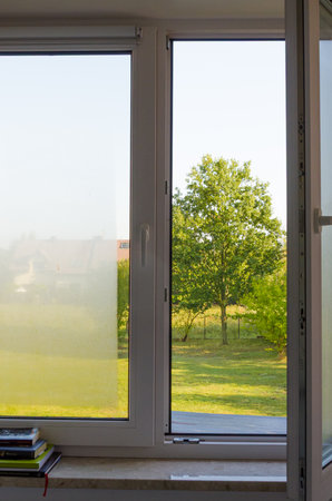 Open window view with outdoor condensation and fog on sunny countryside morning