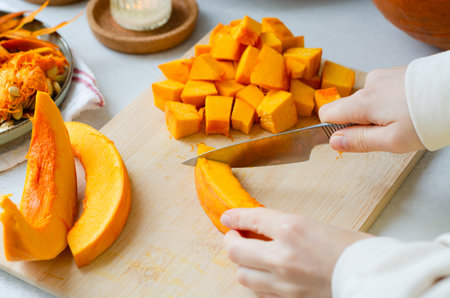 Close up of woman cutting pumpkin into cubes for autumn recipes