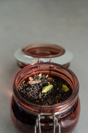 Masala black spiced tea with cardamom and cloves in open glass storage jar close up