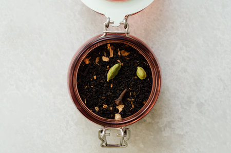 Masala black spiced tea with cardamom and cloves in open glass storage jar top viewの写真素材