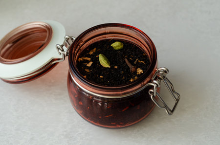 Masala black spiced tea with cardamom and cloves in open glass storage jar close upの写真素材