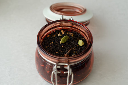 Masala black spiced tea with cardamom and cloves in open glass storage jar close upの写真素材
