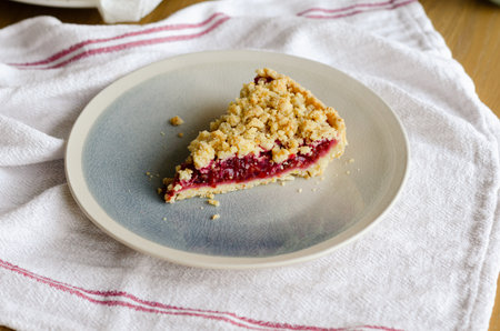 Close up of Italian sbriciolata crumble pie slice with organic plum jam on plate over white towelの写真素材