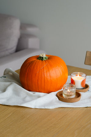 Minimal autumn table decor with pumpkin on linen runner and candles for Halloweenの写真素材