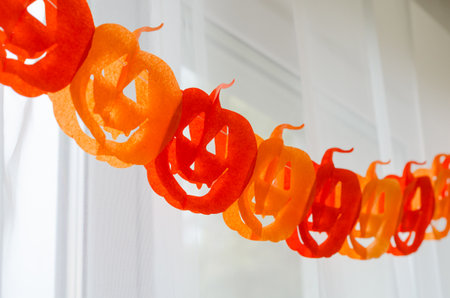 Paper pumpkin garland hanging on window curtains for Halloween party decorの写真素材