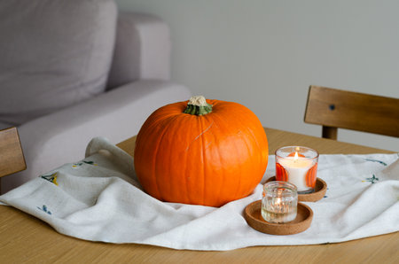 Minimal autumn table decor with pumpkin on linen runner and candles for Halloweenの写真素材