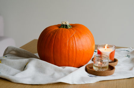 Minimal autumn table decor with pumpkin on linen runner and candles for Halloweenの写真素材