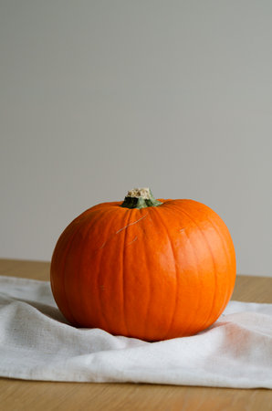 Minimal autumn table decor with pumpkin on linen runner and copy space backgroundの写真素材