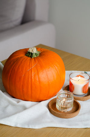 Minimal autumn table decor with pumpkin on linen runner and candles for Halloweenの写真素材