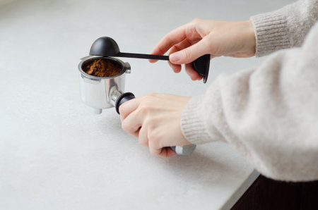 Cozy morning with womans hands scooping ground coffee into portafilter coffee machineの写真素材