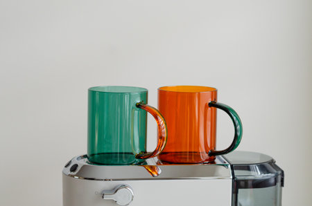 Cozy morning with green and orange glass cups warming on white portafilter coffee machine for home coffee preparationの写真素材