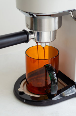 Cozy morning with coffee pouring into orange glass cup from portafilter coffee machine at homeの写真素材