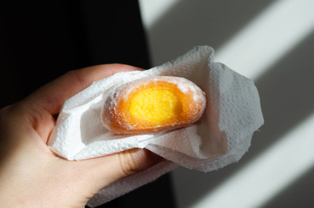 Close-up of person holding a yellow mochi with mango fillingの写真素材
