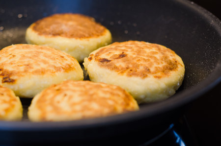 Hot golden cottage cheese pancakes syrniki freshly cooked on a frying panの写真素材