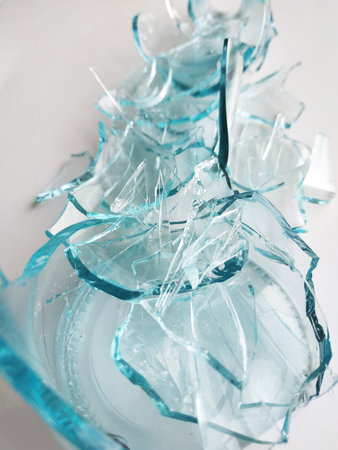 Glass transparent bottle on a white gray background broken into many fragments. Blue is a lot of...