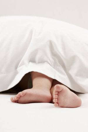 Baby feet in white sheetの写真素材