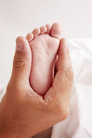 Dad holding baby feet in white sheetの写真素材