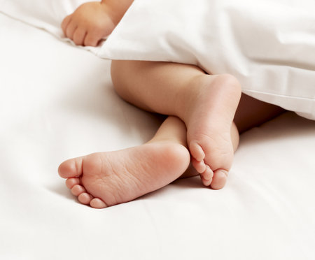 Baby feet on white sheetの写真素材