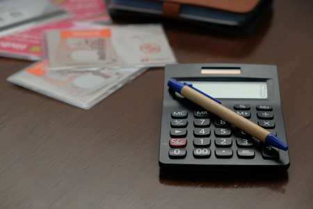 Thailand Bangkok 27 May 2020 : Many accounting books are placed on a wooden table, with a black calculator to calculate expenses.の写真素材