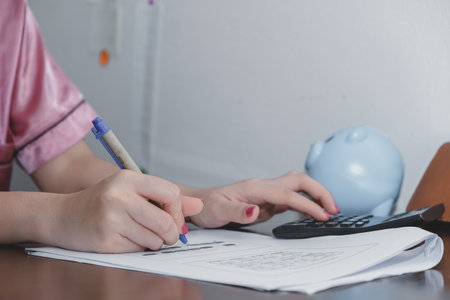 Financial data analyzing hand writing and counting on calculator at home on wooden desk,Business and finance concept.の写真素材