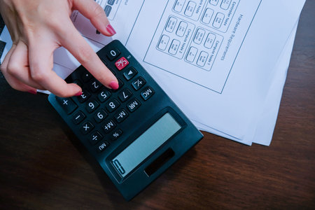 High view of Financial data analyzing hand writing and counting on calculator at home on wooden...