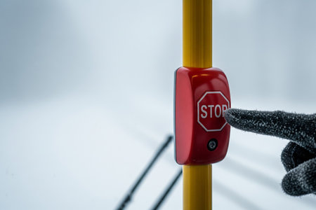 Passenger in a glove pressing the red stop button on a bus with a snowy winter background and copy spaceの素材