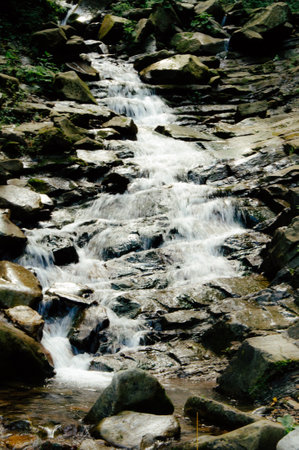 A beautiful view of water flowing at a high rate over bedrock forming waterfalls on the way down the mountain. High quality photoの写真素材