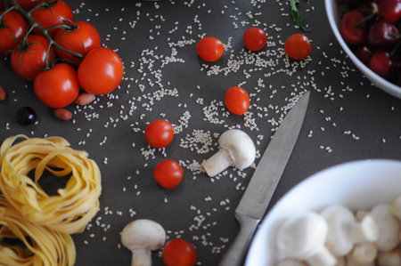 Spaghetti and fettuccine with ingredients for cooking pasta on wooden table with blank of round wooden kitchen board, top view. Rustic style. Flat lay. High quality photoの写真素材