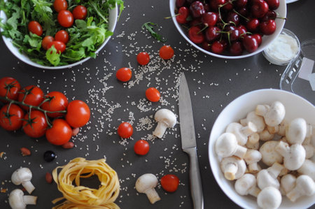 Spaghetti and fettuccine with ingredients for cooking pasta on wooden table with blank of round wooden kitchen board, top view. Rustic style. Flat lay. High quality photoの写真素材