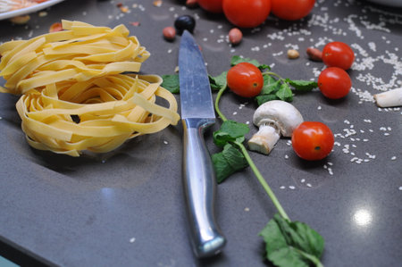 Spaghetti and fettuccine with ingredients for cooking pasta on wooden table with blank of round wooden kitchen board, top view. Rustic style. Flat lay. High quality photoの写真素材