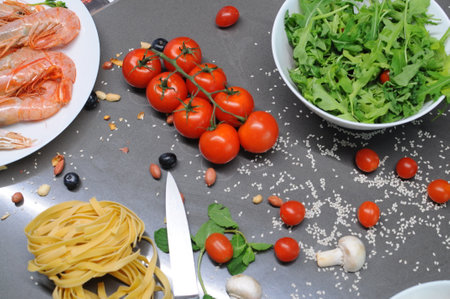 Spaghetti and fettuccine with ingredients for cooking pasta on wooden table with blank of round wooden kitchen board, top view. Rustic style. Flat lay. High quality photoの写真素材