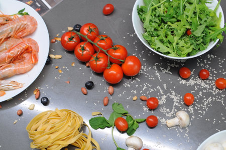 Spaghetti and fettuccine with ingredients for cooking pasta on wooden table with blank of round wooden kitchen board, top view. Rustic style. Flat lay. High quality photoの写真素材