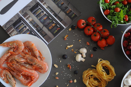 Spaghetti and fettuccine with ingredients for cooking pasta on wooden table with blank of round wooden kitchen board, top view. Rustic style. Flat lay. High quality photoの写真素材