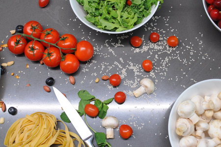 Spaghetti and fettuccine with ingredients for cooking pasta on wooden table with blank of round wooden kitchen board, top view. Rustic style. Flat lay. High quality photoの写真素材