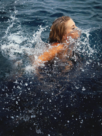 A young woman lying on the seashore is covered by a wave
