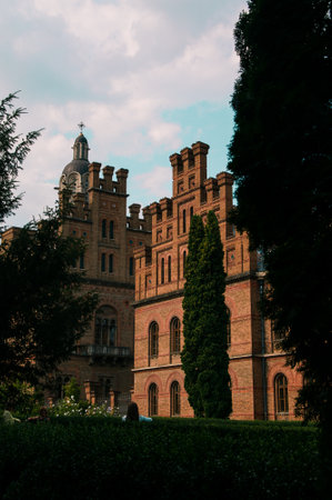 Chernivtsi National University, Residence of Bukovinian and Dalmatian Metropolitans in the city of Chernivtsi, Ukraine. Red brick facade with green trees and bushes at sunny day. High quality photoの写真素材