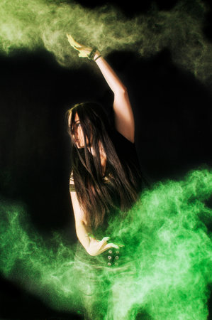 Young woman in a colorful powder fest, with powder covering her face and a cloud of dust. On black with rainbow bursts of color. High quality photoの写真素材