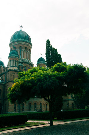 Chernivtsi National University, Residence of Bukovinian and Dalmatian Metropolitans in the city of Chernivtsi, Ukraine. Red brick facade with green trees and bushes at sunny day. High quality photoの写真素材