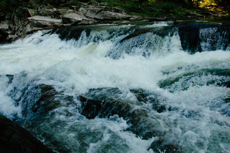 A beautiful view of water flowing at a high rate over bedrock forming waterfalls on the way down the mountain. High quality photoの写真素材