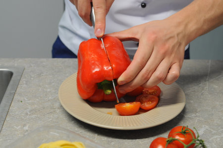 Closeup of hands of chef cook cutting vegetables on wooden tableの写真素材