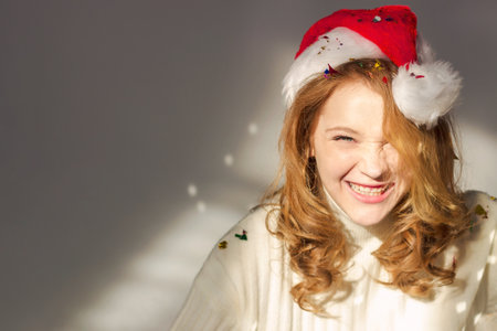 A beautiful young girl model with red hair smiles. Confetti is everywhere. It shimmers in the sun. High quality horizontal photo with copy space for textの写真素材
