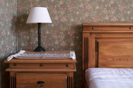 Interior design detail of a luxury country hotel room with wooden bed and bedside table. Floral...