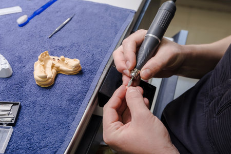 Dental technician hands or dentist working with tooth dentures in his laboratory. High quality...