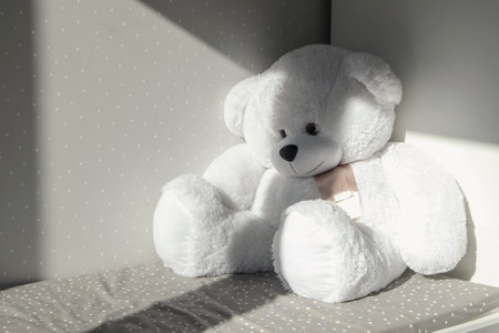 White big soft bear toy sitting on the child bed in the room. Sunlight falls on it.の写真素材