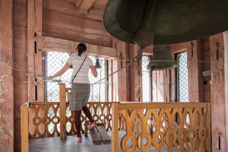 Bell ringer a woman rings the bells. Christian Voznesenskiy Cathedral in the center of Almaty city. Orthodox christian church. The bell tower of the Cathedral. Panfilov parkの写真素材