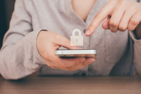 Woman is holding smart phone in the hand and trying to unlock it. Lock is on the screen. Cyber security, hacker attack, antivirus and digital technology concept.の写真素材