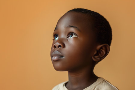 Portrait of a child black boy against a light brown background.の素材