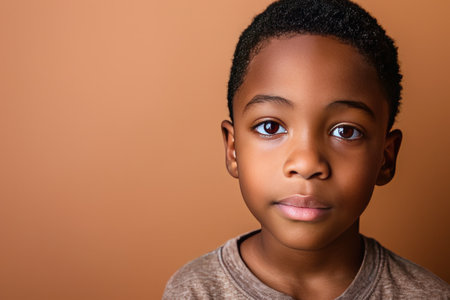 Portrait of a child black boy against a light brown background.の素材