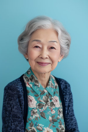 Smiling elderly Japanese woman on pale blue color background.の素材